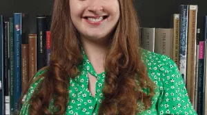 Woman in a green shirt smiling in front of a bookshelf