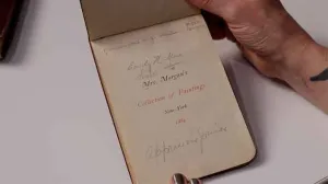 video still of woman's hand holding a catalog open, reads Mrs. Morgan's Collection of Paintings, New York, 1884