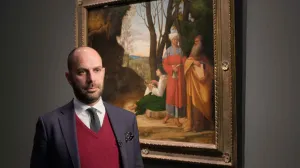 video still of Xavier Salomon standing in front of painting of three men