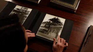 video still of woman looking over archival image