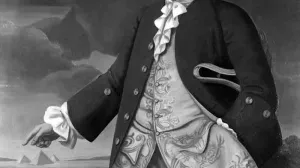Three-quarter-length portrait of a man against a landscape, pointing to three pyramids.