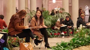 two women sitting and sketching in the Garden Court of the Frick Collection