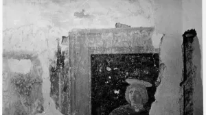 Corner of a room with a section of fresco depicting the head and shoulders of a young blond man.