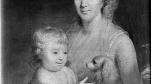 A woman holding a young child and a small spaniel on her lap.