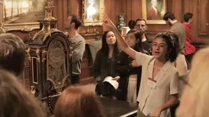 video still of instructor talking and pointing in gallery with crowd