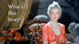video still of What's Her Story, woman wearing orange colored dress, sitting in chair