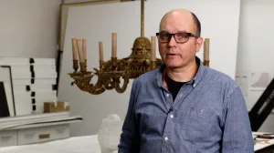 video still of Arthur Fowler standing in front of chandelier