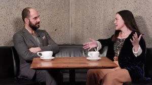 video still of Xavier Salomon and Jenna Gribbon seated and talking