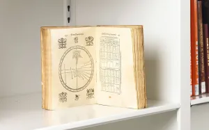 Book on a shelf open to a page featuring celestial maps and a table of figures