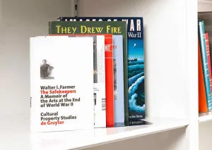Six books about art and World War Two stacked on a white shelf