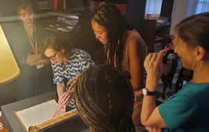Group gathered around an archival book on a desk