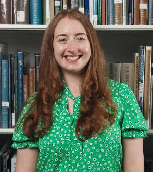 Woman in a green shirt smiling in front of a bookshelf