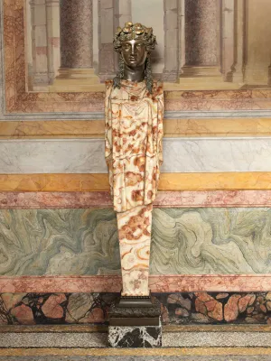 A sculpture with a body carved from variegated red and white marble, and the head of a woman that is cast from bronze