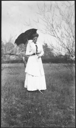 Black and white image of Adelaide Frick in a white dress holding a parasol