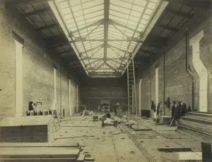 black and white photograph of frick east gallery under construction showing brick walls, unfinished flooring and ladder