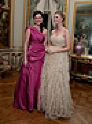 two women dressed in evening gowns, one in fuchsia, the other in white