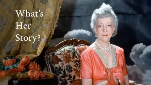 video still of What's Her Story, woman wearing orange colored dress, sitting in chair