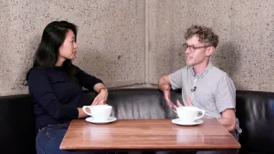 video still of Aimee Ng and Doron Langberg sitting while talking