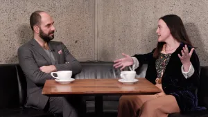 video still of Xavier Salomon and Jenna Gribbon seated and talking