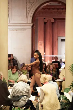 artist model posing in The Frick Collection, with sketching patrons surrounding
